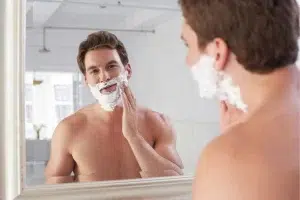 Homme se mettant de la mousse à raser face à un miroir